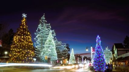 A view of a street in Big Bear Lake with multiple Christmas trees covered in colorful lights.