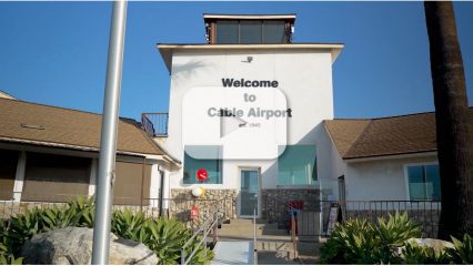 A shot of the "Welcome to Cable Airport" sign on a building with glass doors and windows.