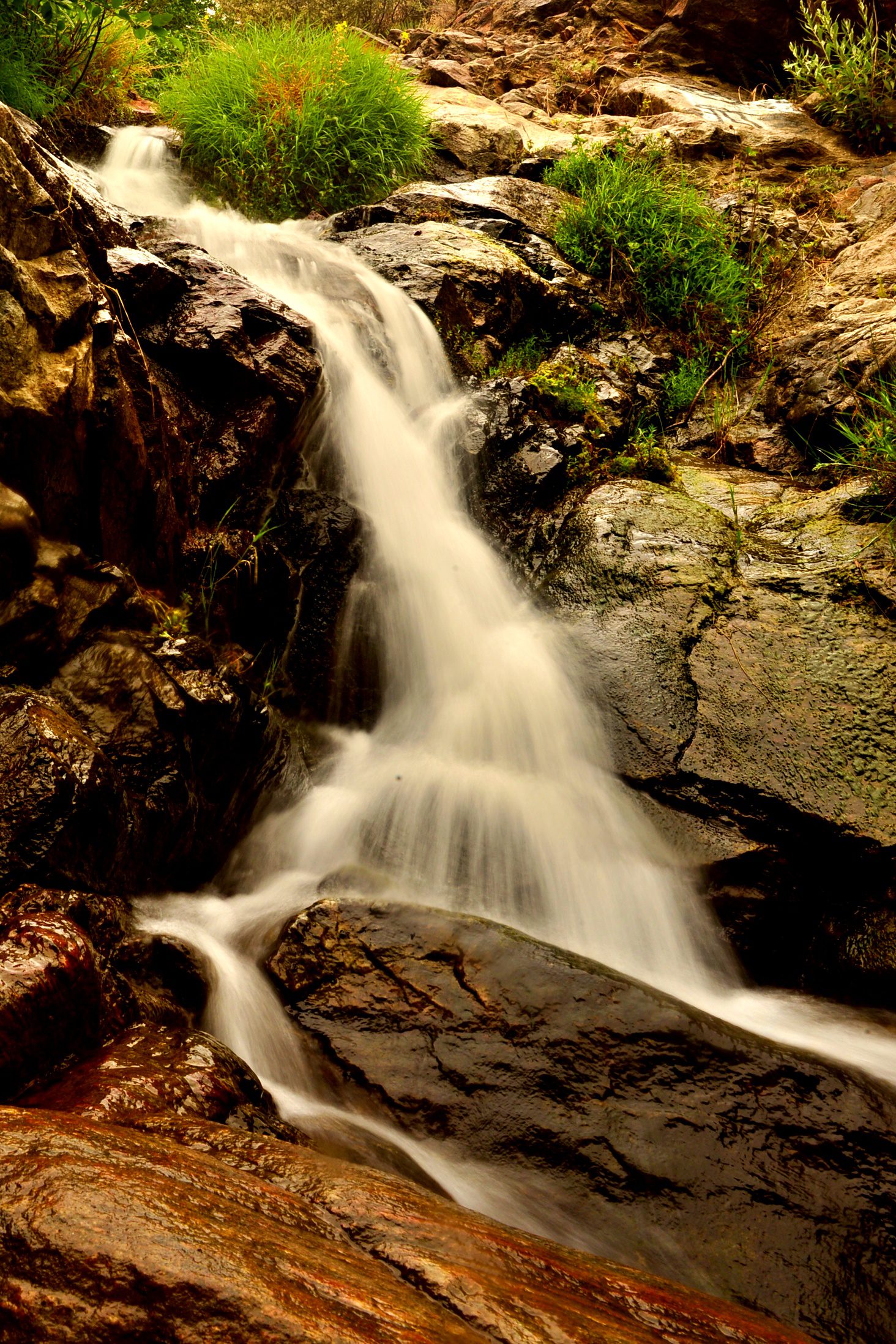 A waterfall cascading over rocky terrain surrounded by lush greenery.