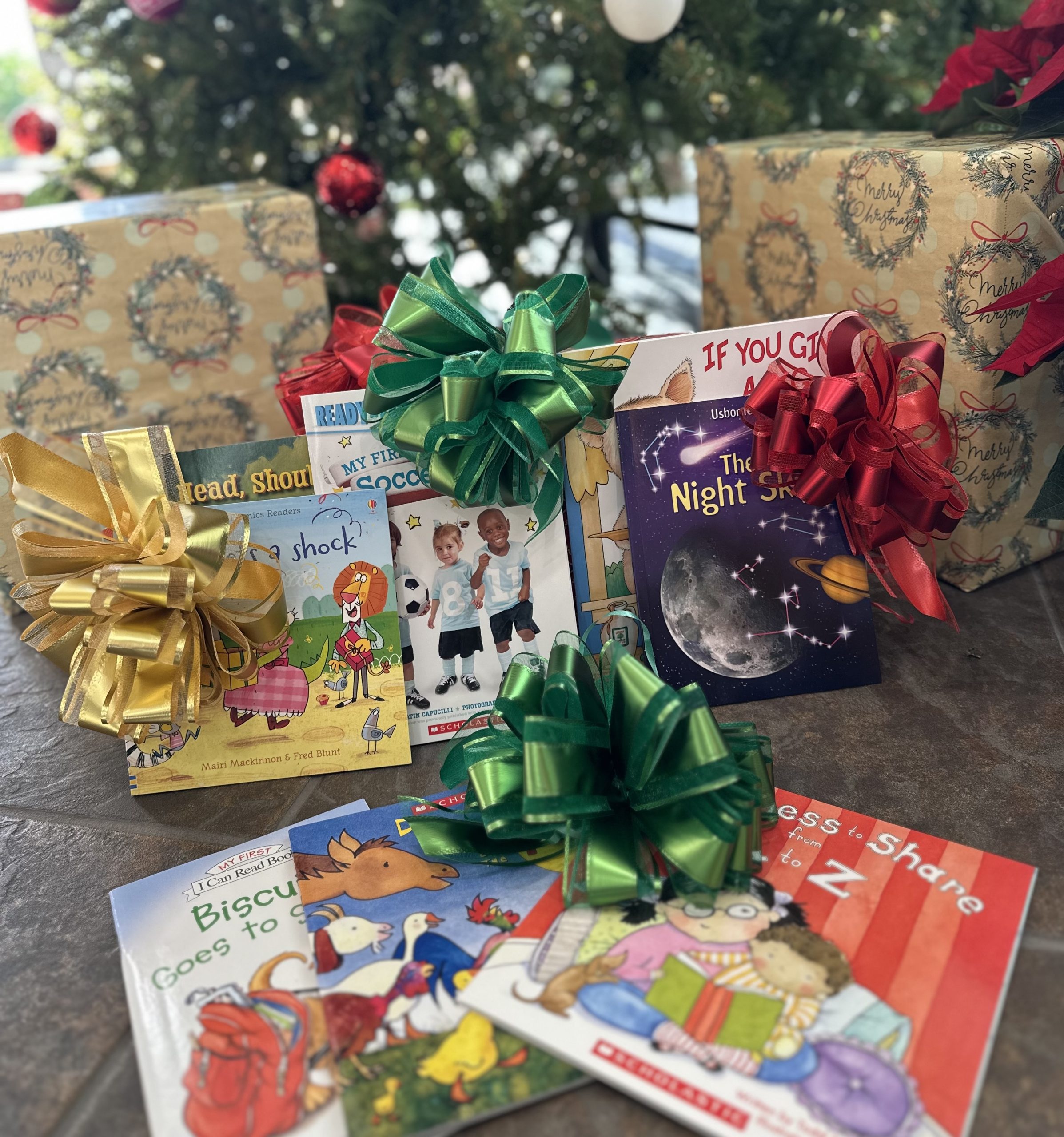 Children’s books with colorful bows under a Christmas tree.