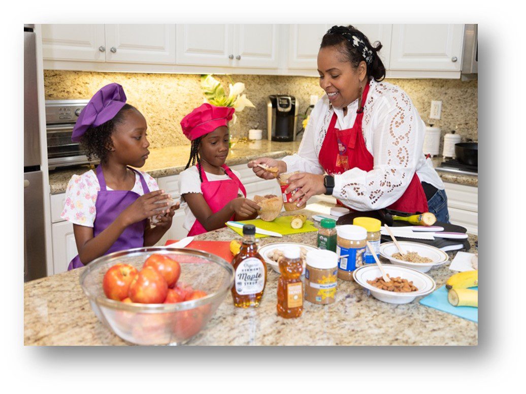 A woman and two girls in a kitchen cooking healthy food.