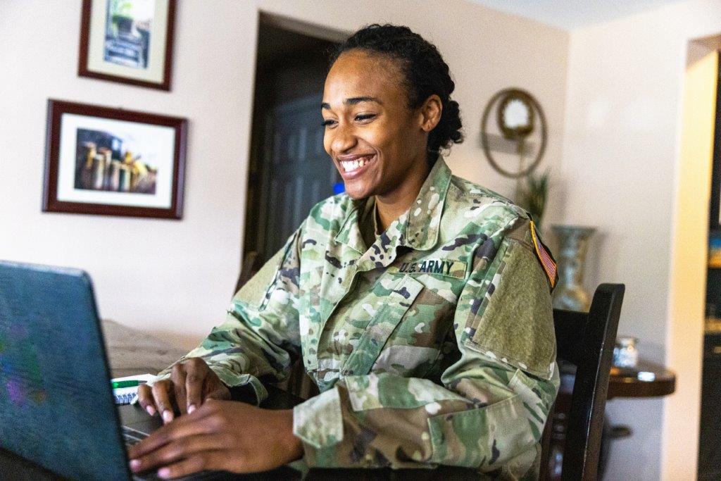 A person in military uniform using a computer.