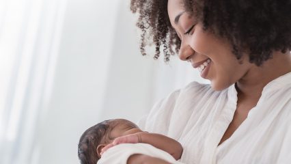 An African American mother smiles as she cradles her baby.