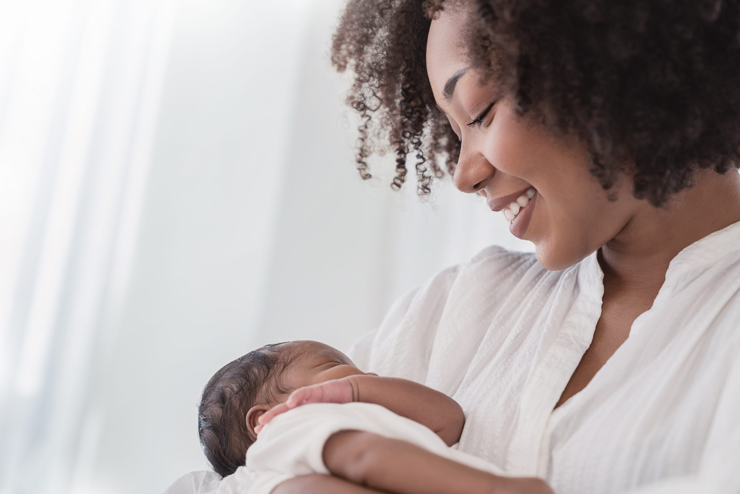 An African American mother smiles as she cradles her baby.