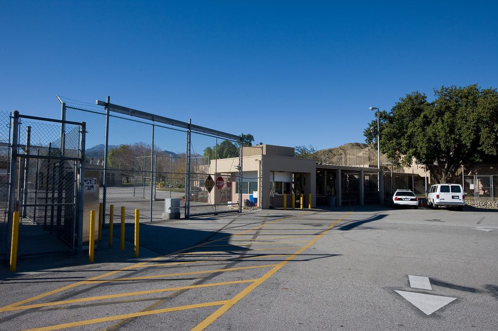 Entrance to Glen Helen Rehabilitation Center, with security fencing, a guard station and County vehicles.
