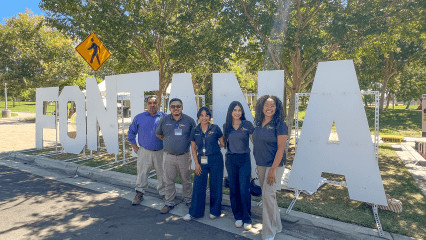 Healthy Communities Initiative staff and city of Fontana partners stand together outdoors near large city letter signage during a community meeting.