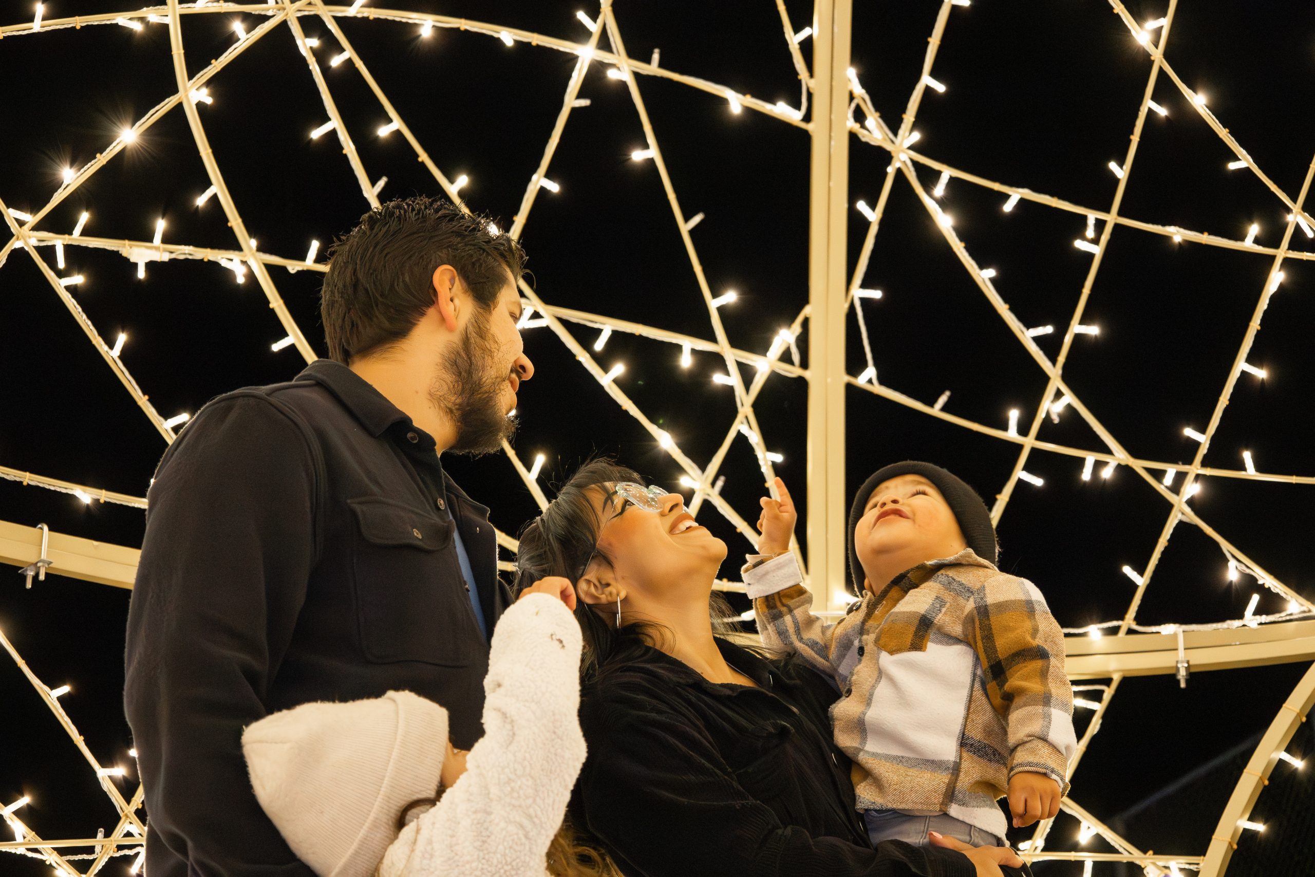 family looking up at lights at Big Bear Alpine Zoo’s Wild Lights display.