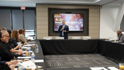 Supervisor Joe Baca, Jr. stands at the front of a conference room, welcoming attendees to his homelessness roundtable.