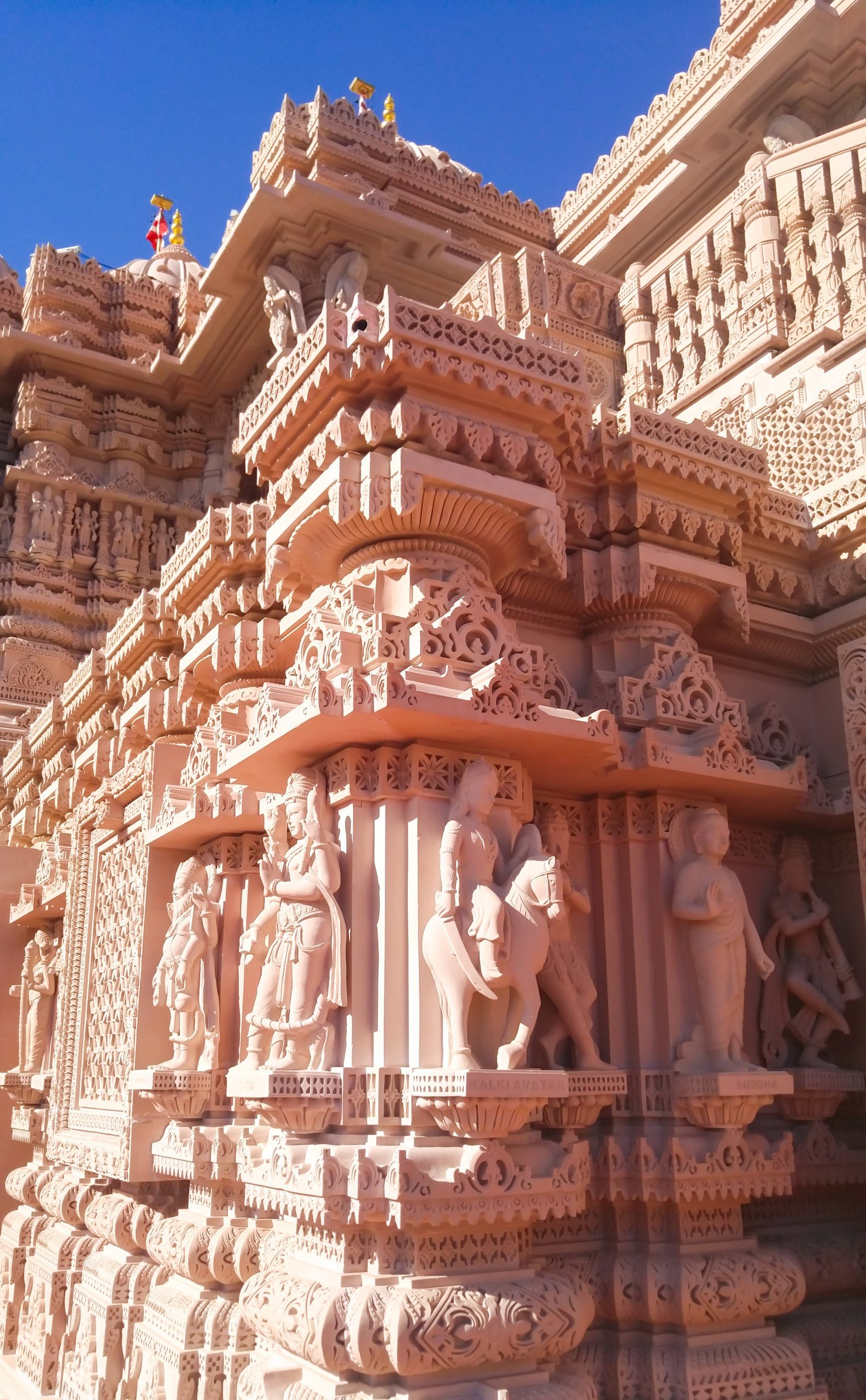 Detailed view of the ornate stone carvings on the BAPS Hindu Temple in Chino Hills, featuring several statues and intricate architectural designs.
