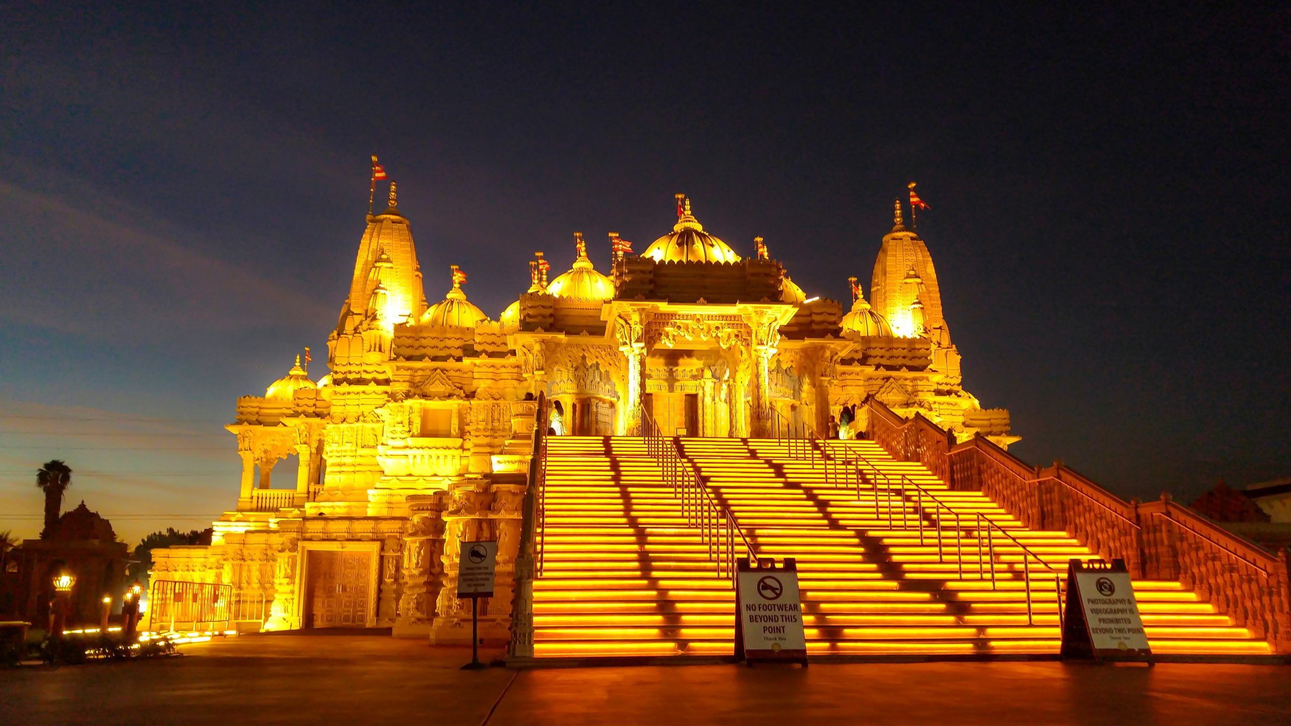 Nighttime view of the BAPS Hindu Temple in Chino Hills, with grand stairs leading up to the main entrance.