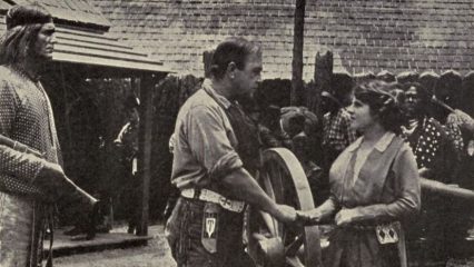A scene from "The Call of the North" shows two people engaged in conversation while others observe.