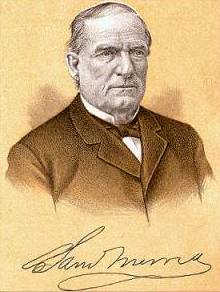 An image of an individual wearing a formal suit with a bow tie. The background is a warm brown color, and there is a signature at the bottom of the image.