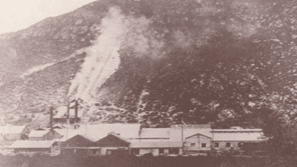 A historical photo of Slover Mountain shows a mining facility at its base, with exposed rock and dust rising from excavation on the slope.