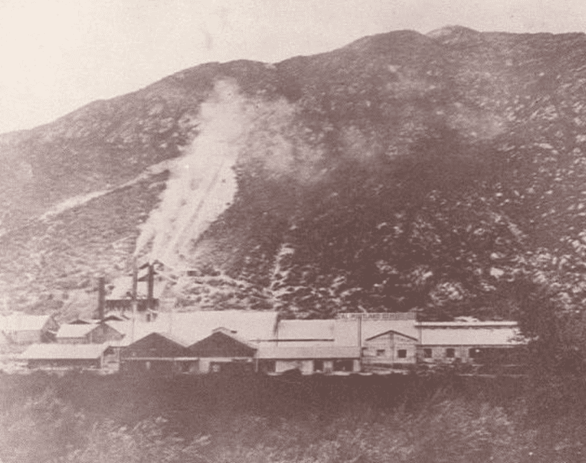 A historical photo of Slover Mountain shows a mining facility at its base, with exposed rock and dust rising from excavation on the slope.