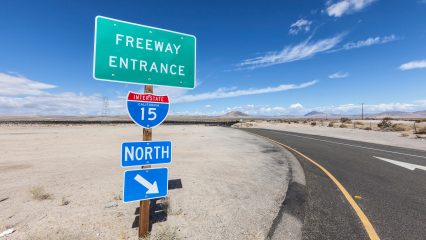 Signs display "Freeway Entrance" and "Interstate 15 North" on a clear day with mountains in the distance.