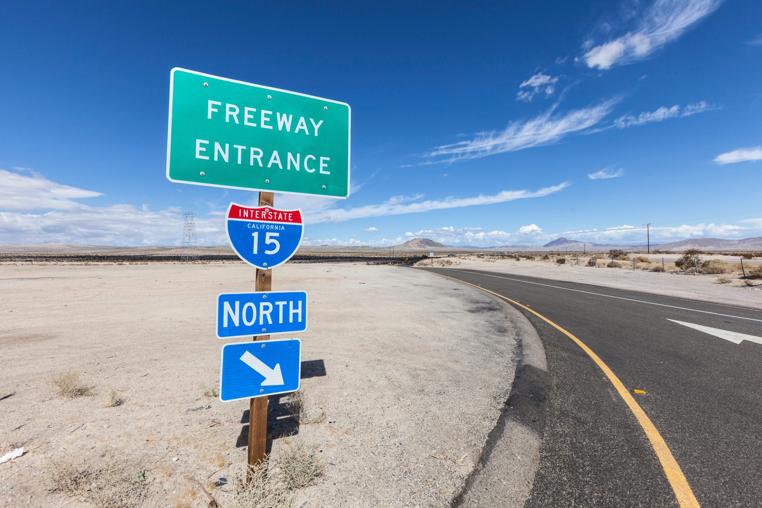 Signs display "Freeway Entrance" and "Interstate 15 North" on a clear day with mountains in the distance.