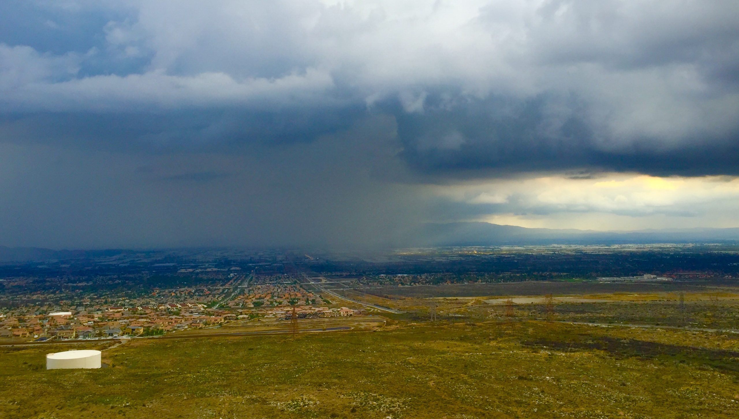 A view of the city from a high vantage point. Dark storm clouds loom over the area.