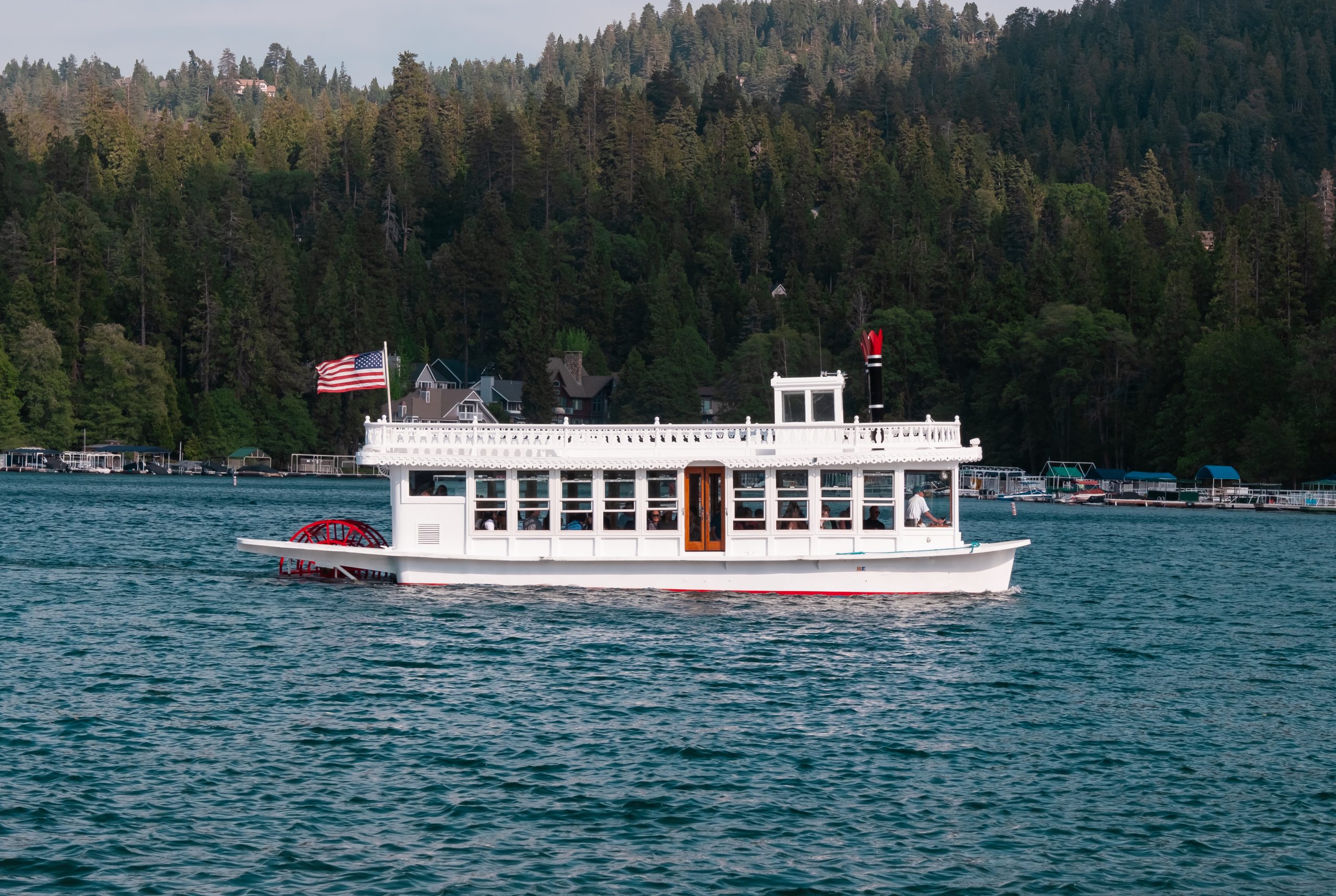 A boat sailing on a lake with a forest in the background.