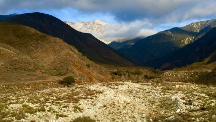 A view of mountainous terrain under a partly cloudy sky.