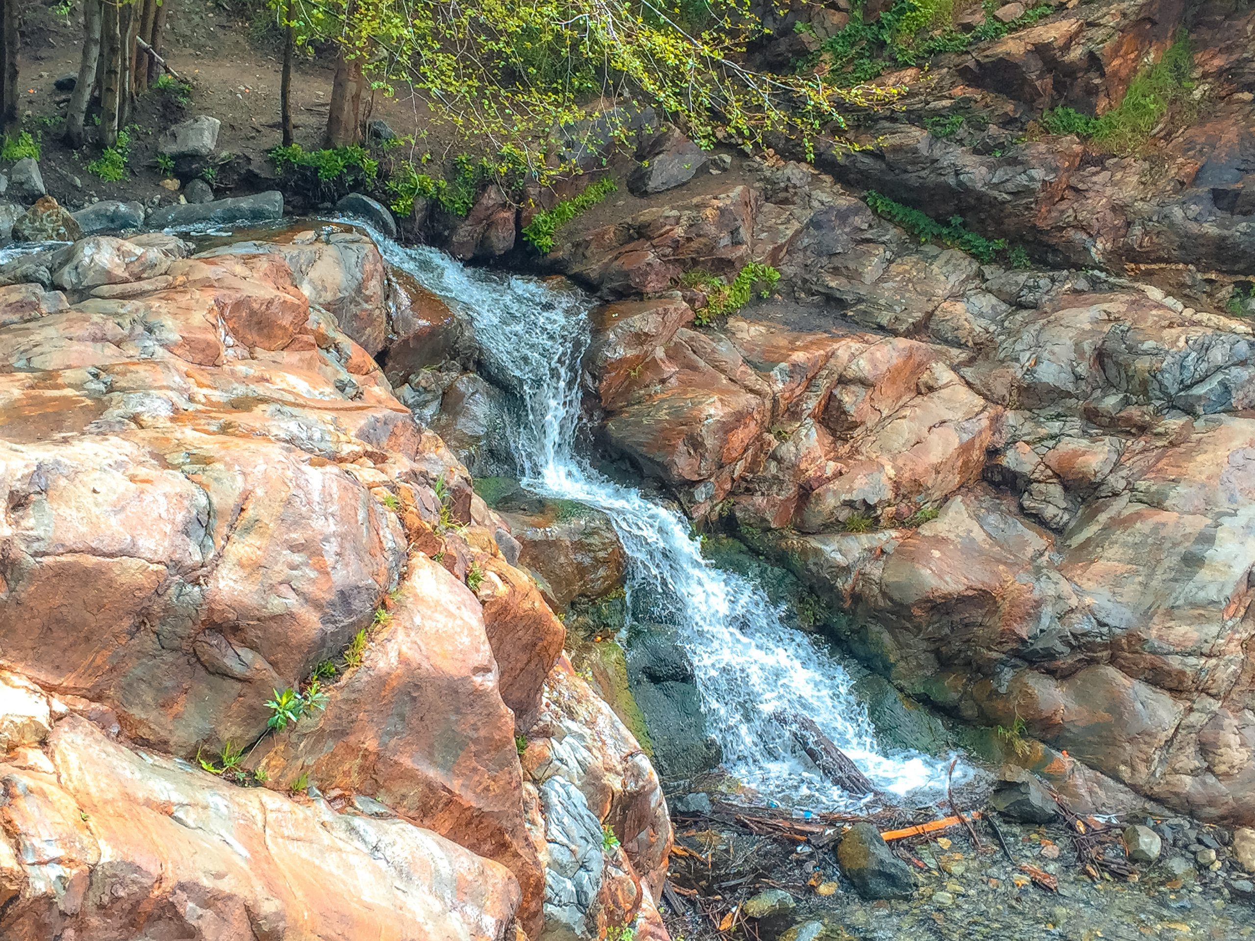 A small waterfall cascading over rocks surrounded by trees.