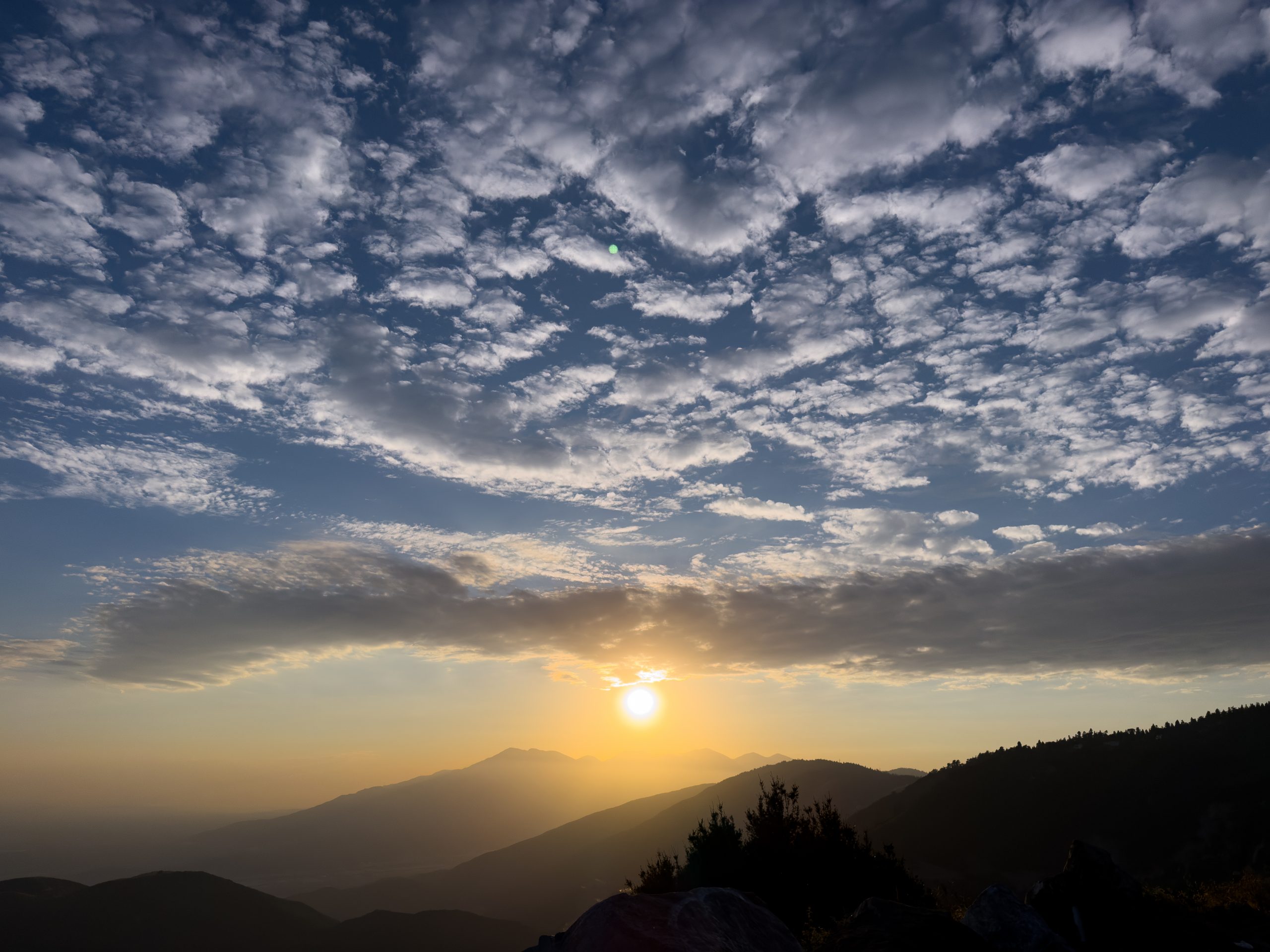 Sunset over a mountain range with a dramatic cloud-filled sky.