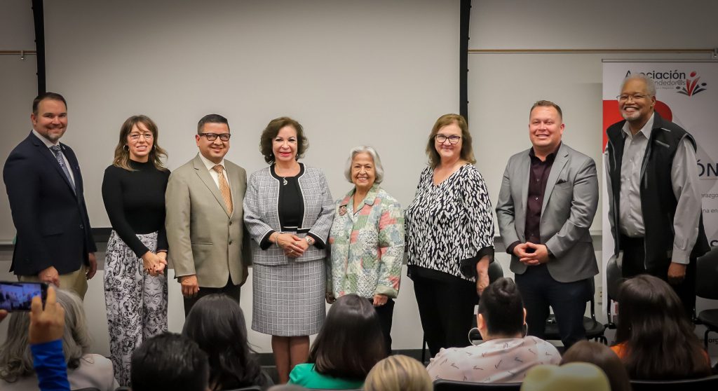 Eight people stand in a row smiling at an event hosted by Asociación de Emprendedor@s.