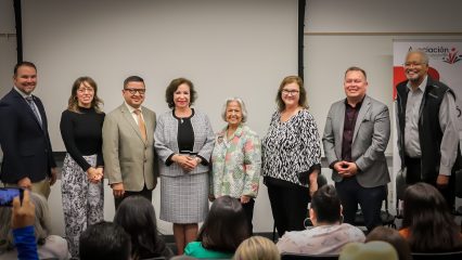 Eight people stand in a row smiling at an event hosted by Asociación de Emprendedor@s.
