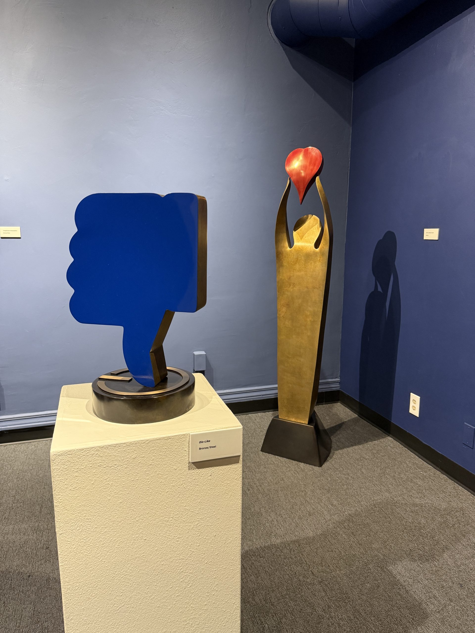 An art installation featuring two sculptures with both displayed against a blue wall.