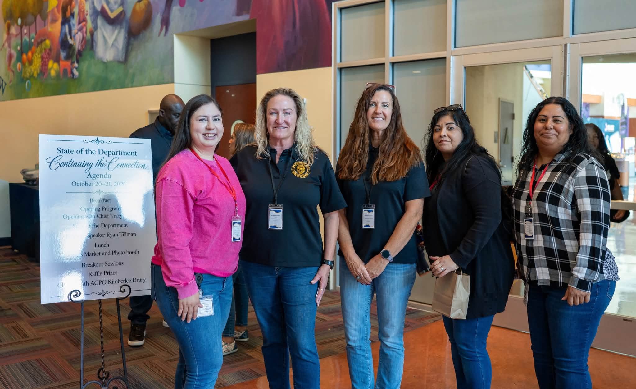 Chief Tracy Reece and Assistant Chief Kimberlee Drury pose with employees near the event agenda.