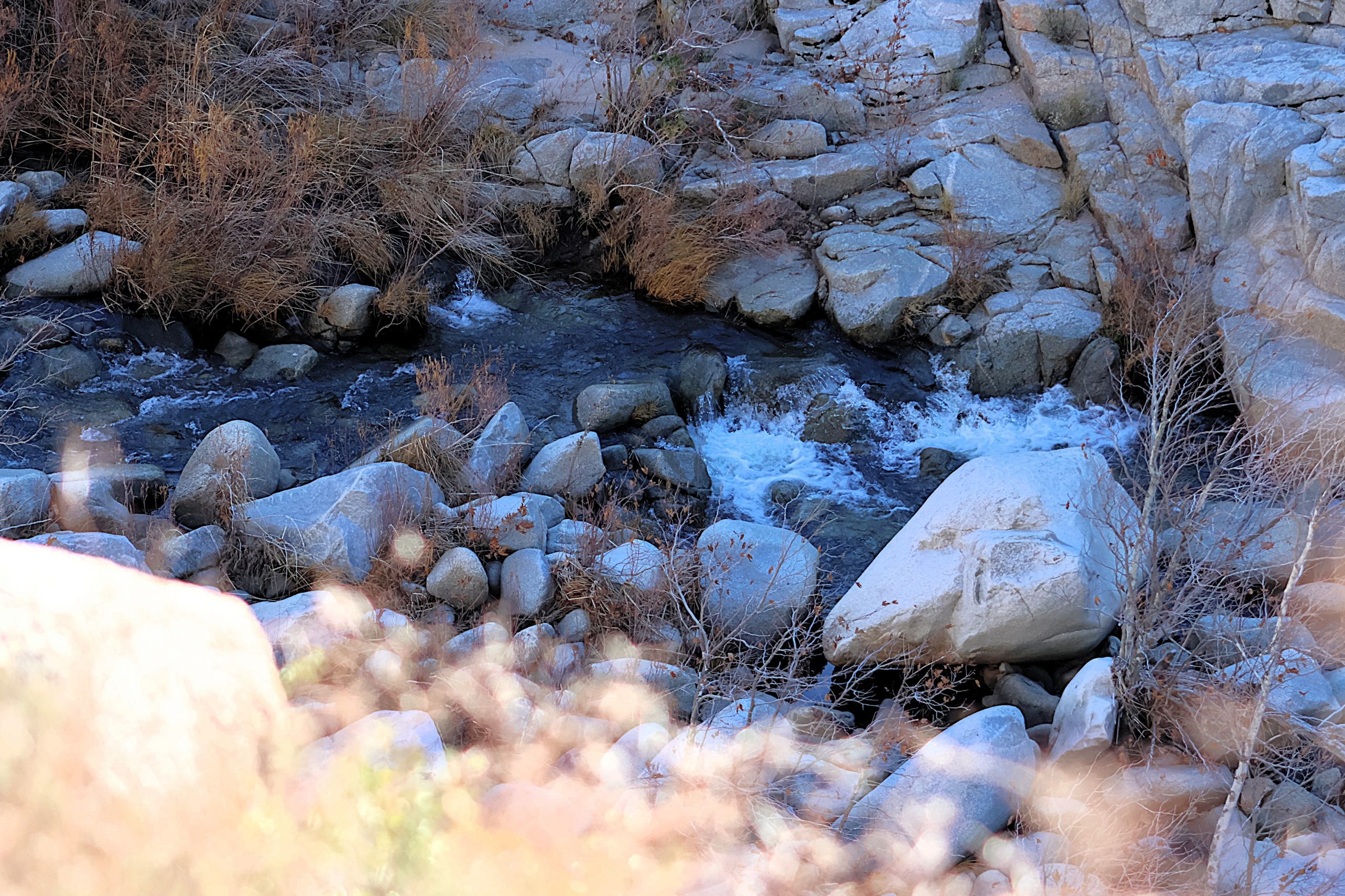 Stream of water flowing through several large rocks.