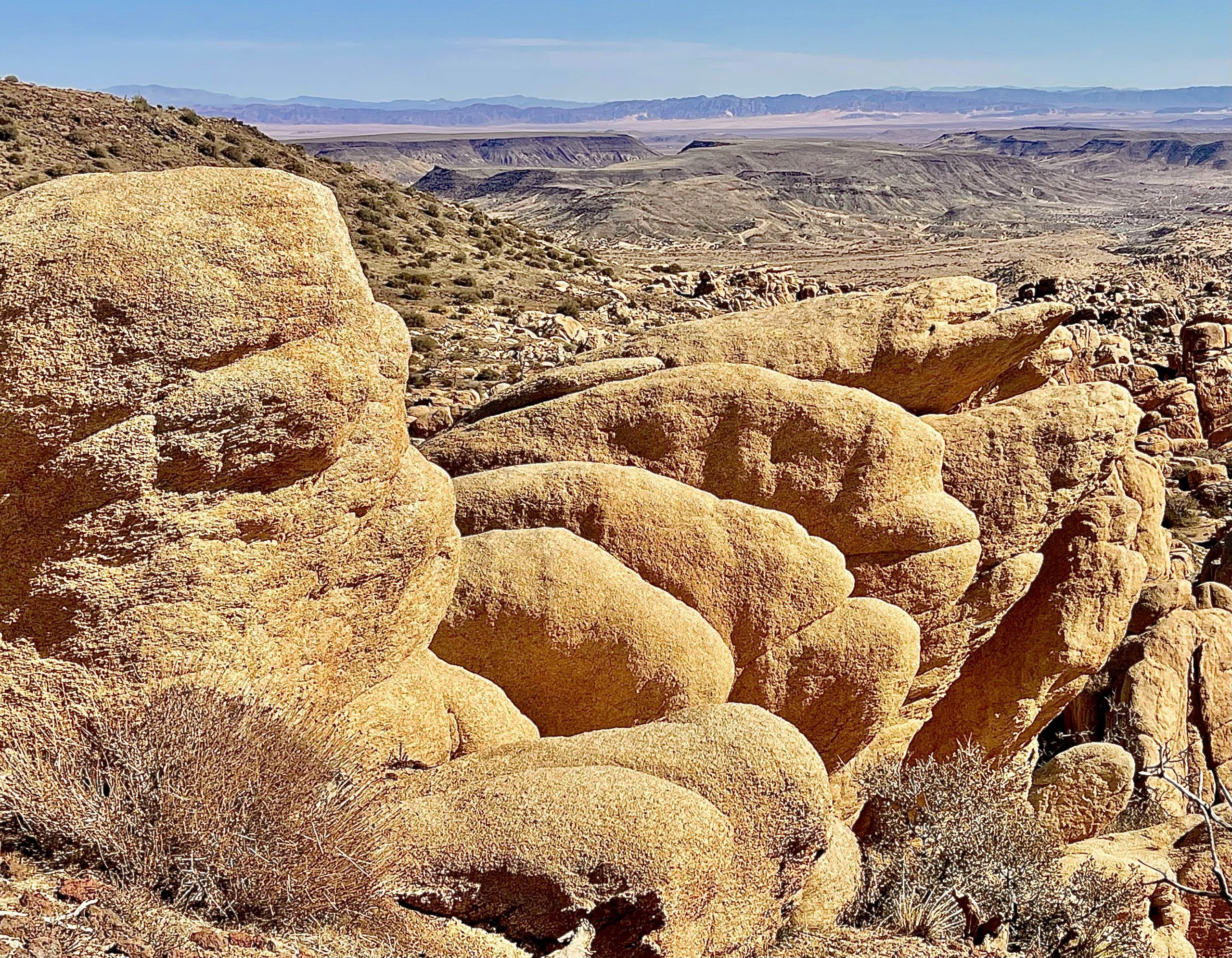 Large rock formations in the foreground with the desert landscape and mountains in the background.