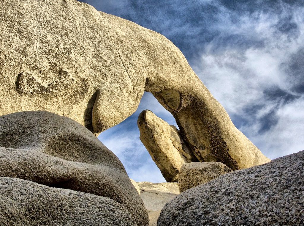 Arch shaped rock formation under a blue sky.