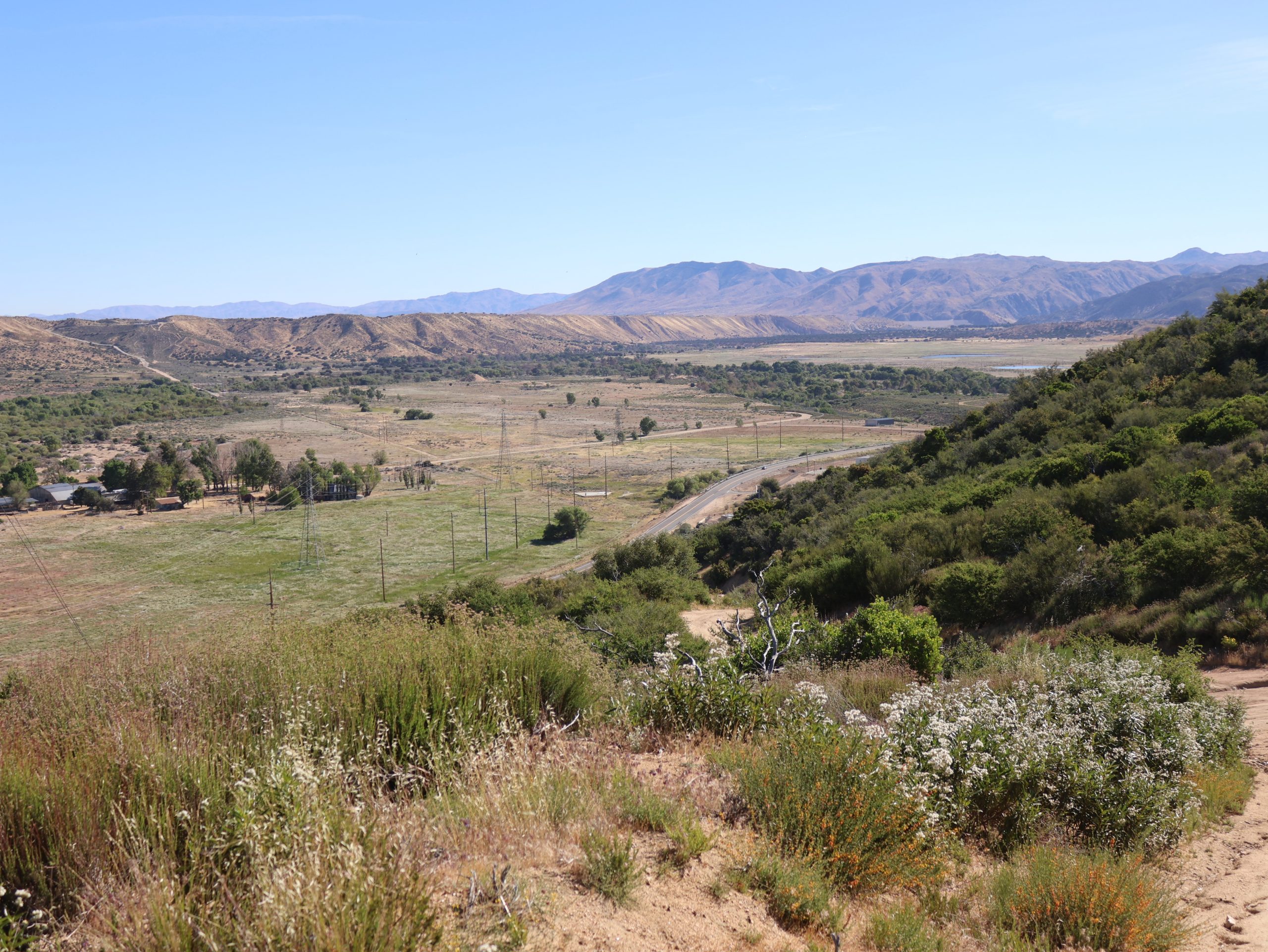 A view of hills with winding roads and mountains in the distance.