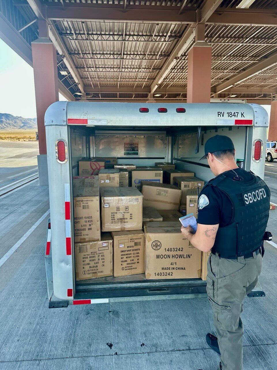 Officer opens trailer loaded with boxes of illegal fireworks during a seizure operation.