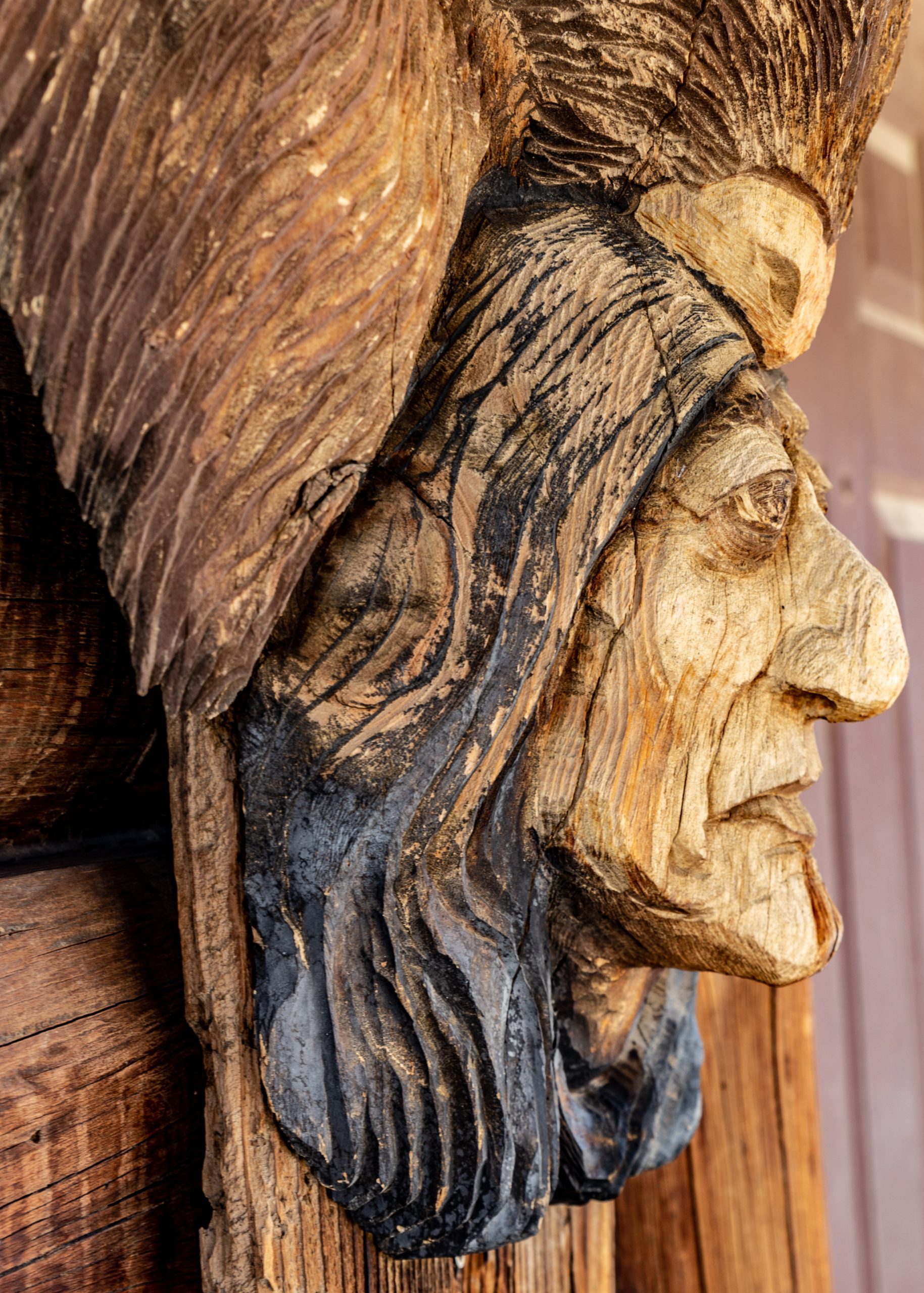 : A wooden carving depicting a Native American wearing a traditional headdress.