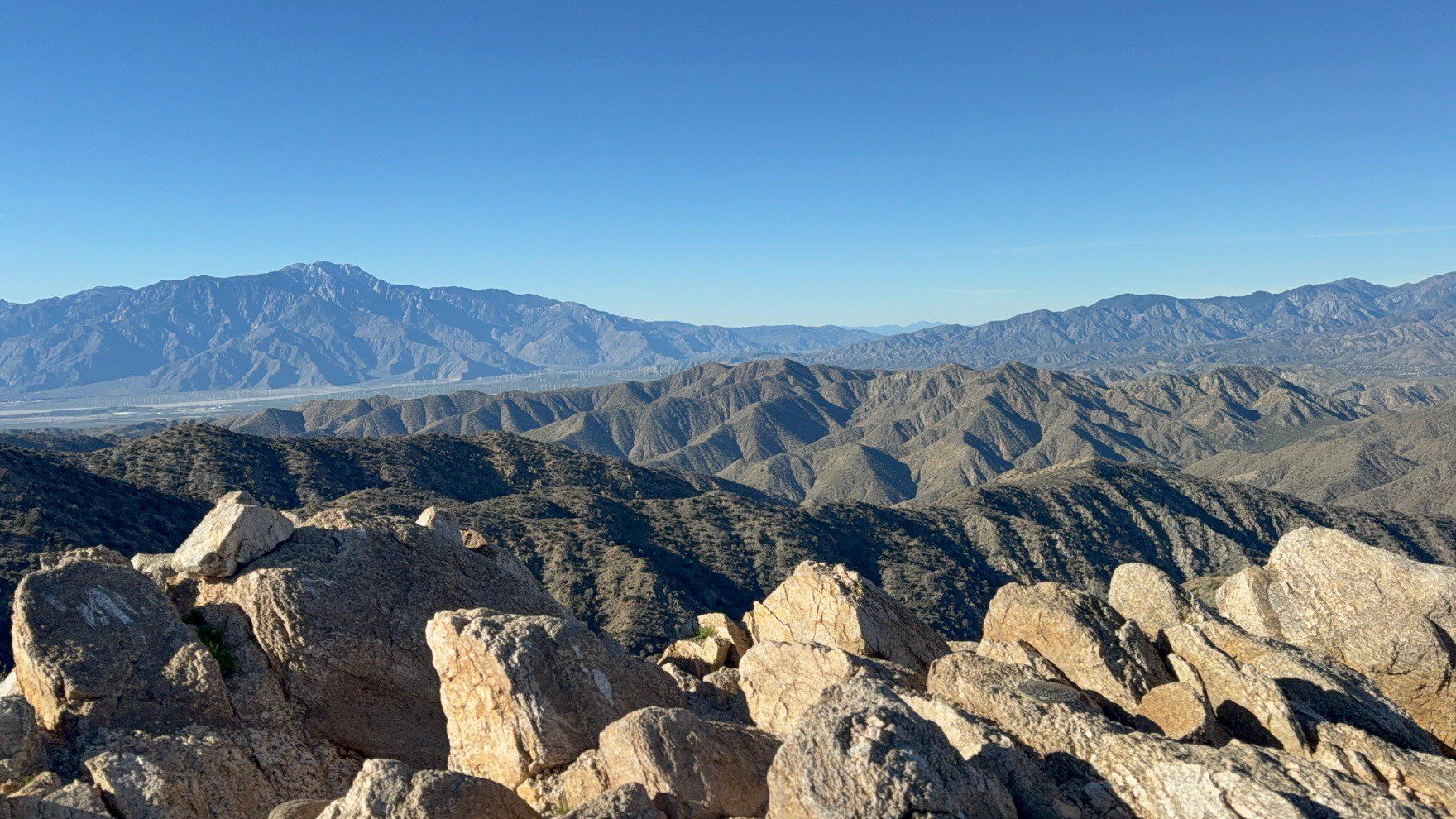 View from Joshua Tree National Park with rocky terrain in the foreground and mountains in the background.
