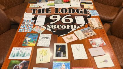 Thank you cards and letters spread across a wooden table at The Lodge 96, SBCoFD, expressing community gratitude to firefighters.