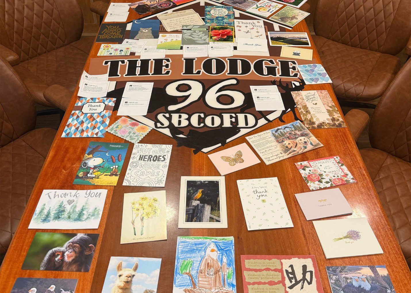Thank you cards and letters spread across a wooden table at The Lodge 96, SBCoFD, expressing community gratitude to firefighters.