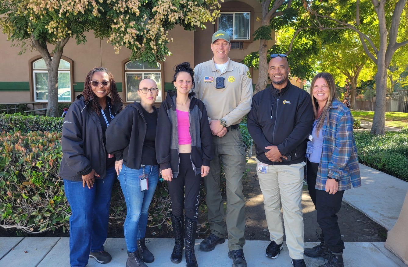 A group of six people are standing outdoors in front of a building.