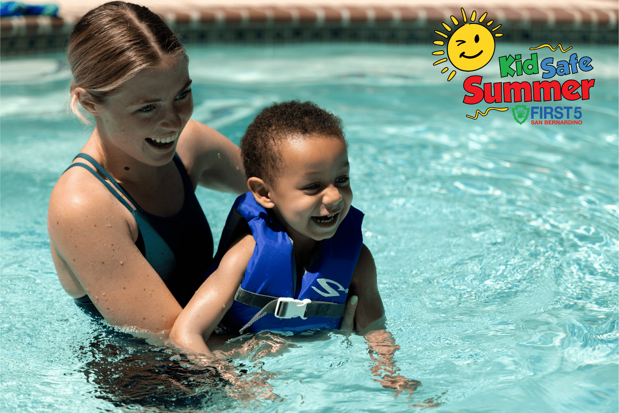 Smiling woman helps a young boy in a blue life vest float in a swimming pool, promoting summer water safety with the “Kid Safe Summer” campaign logo.