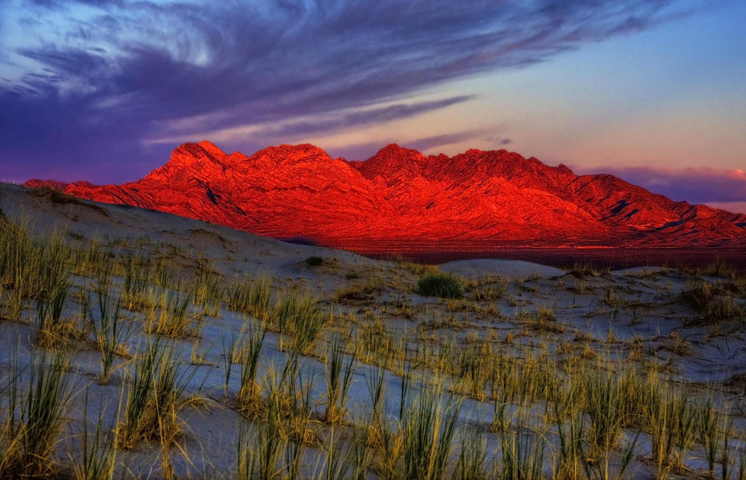 Sunset over Providence Mountain with scattered vegetation below it.