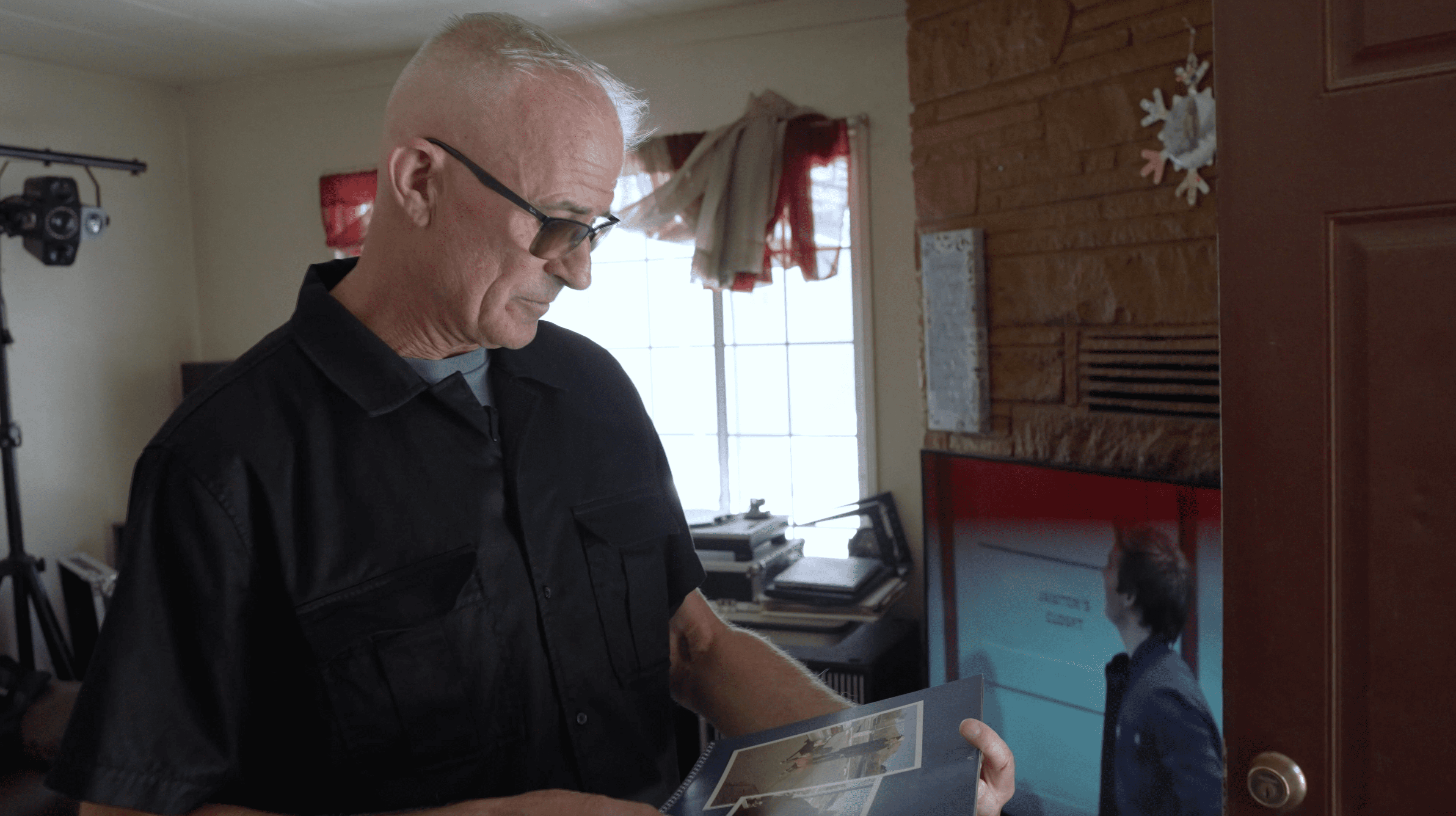 A man looking at a photo album in a room with a television.