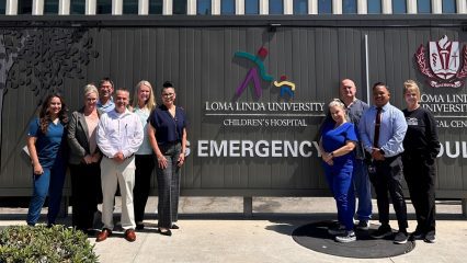 A group of healthcare and emergency medical services staff standing outside in front of the Loma Linda University Children's Hospital Emergency sign.