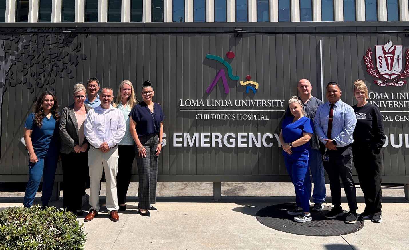 A group of healthcare and emergency medical services staff standing outside in front of the Loma Linda University Children's Hospital Emergency sign.