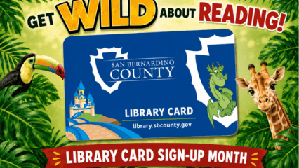 Text reads Get Wild About Reading! promoting Library Card Sign-Up Month. A San Bernardino County Library card is centered among tropical leaves, with a toucan on the left and a giraffe on the right with the website URL, li-brary.sbcounty.gov.