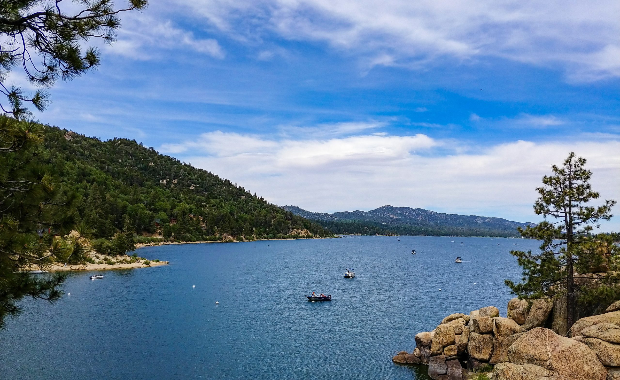 View of Big Bear Lake with boats on the water and mountains in the background.