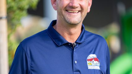Aaron Speer smiling outdoors in a navy polo with the Public Works Special Districts logo.