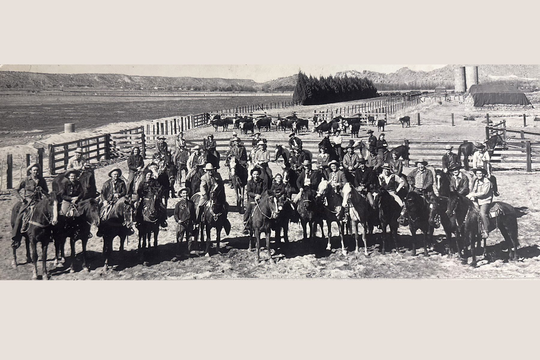 A large group of cattle ranchers sitting on their horses in a ranch corral setting.