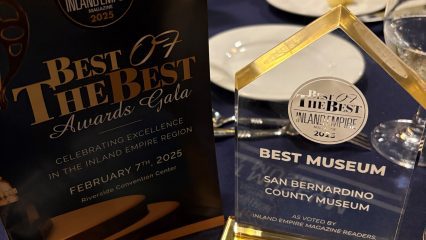 An elegant table display at the 'Best of the Best Inland Empire 2025' Awards Gala, highlighting an award presented to the San Bernardino County Museum for 'Best Museum,' with a program booklet and certificate on a navy blue tablecloth.