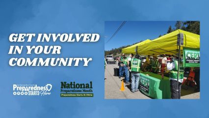 Community Emergency Response Team (CERT) volunteers in green vests gather under a bright yellow canopy at a local preparedness event, speaking with residents about emergency readiness.